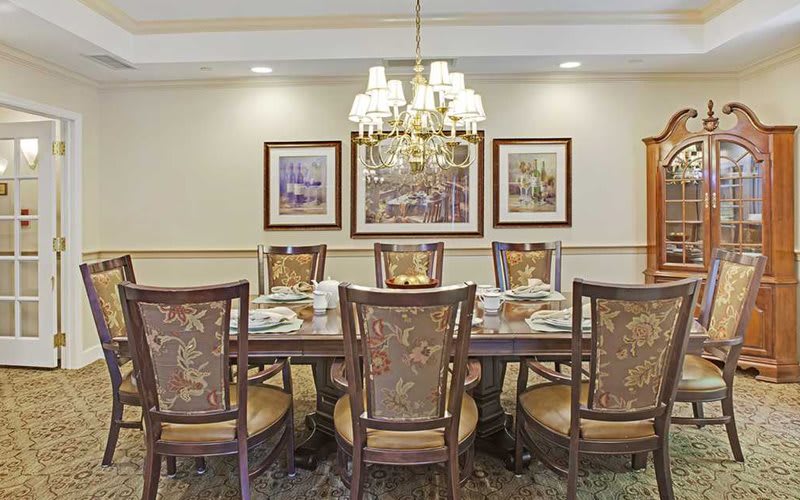 A traditional dining room with a large table, ornate chairs, and a decorative chandelier.