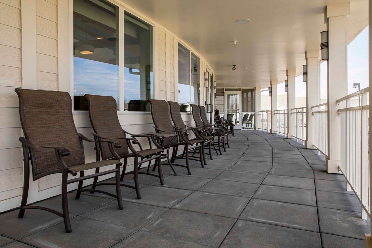 A row of chairs on a spacious outdoor patio with a covered roof.