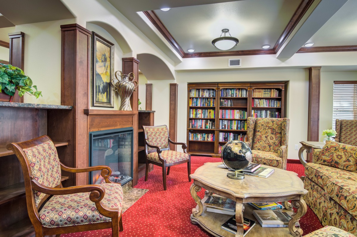 A cozy library reading area with bookshelves, armchairs, and a globe on a table.