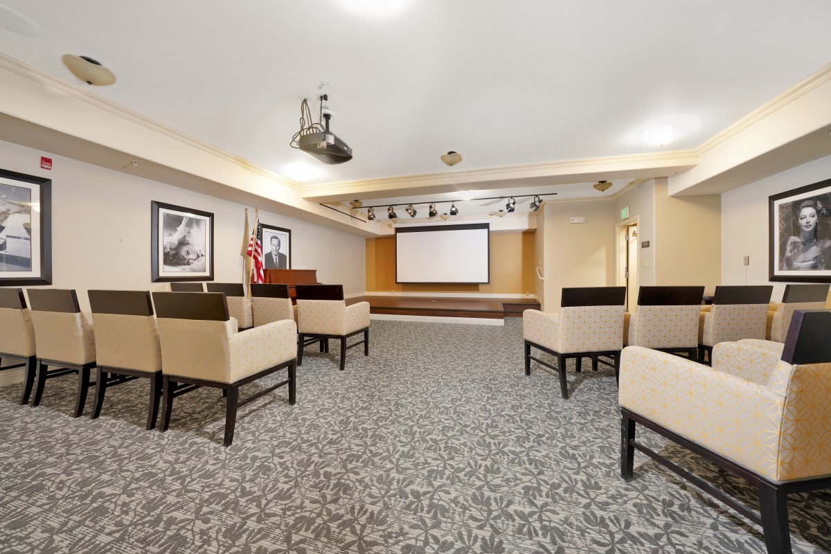 A well-equipped conference room with seating and a projector screen for presentations.