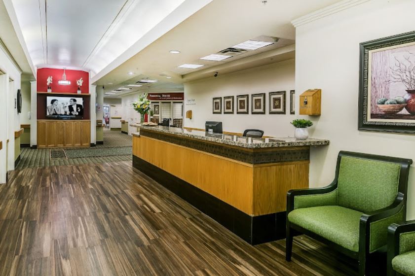A modern office reception area with a wooden desk and seating.