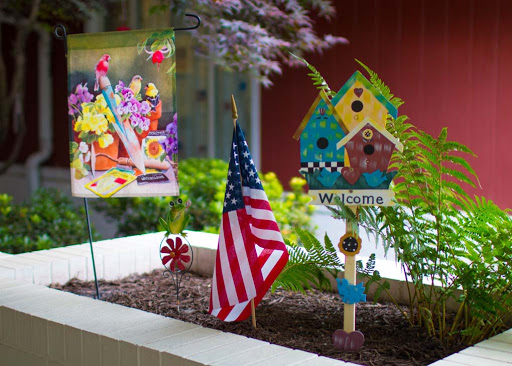 A vibrant garden display featuring a welcoming atmosphere with colorful decorations and an American flag.