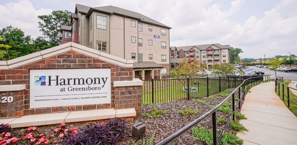An exterior view of a residential apartment building with a sign in the foreground.