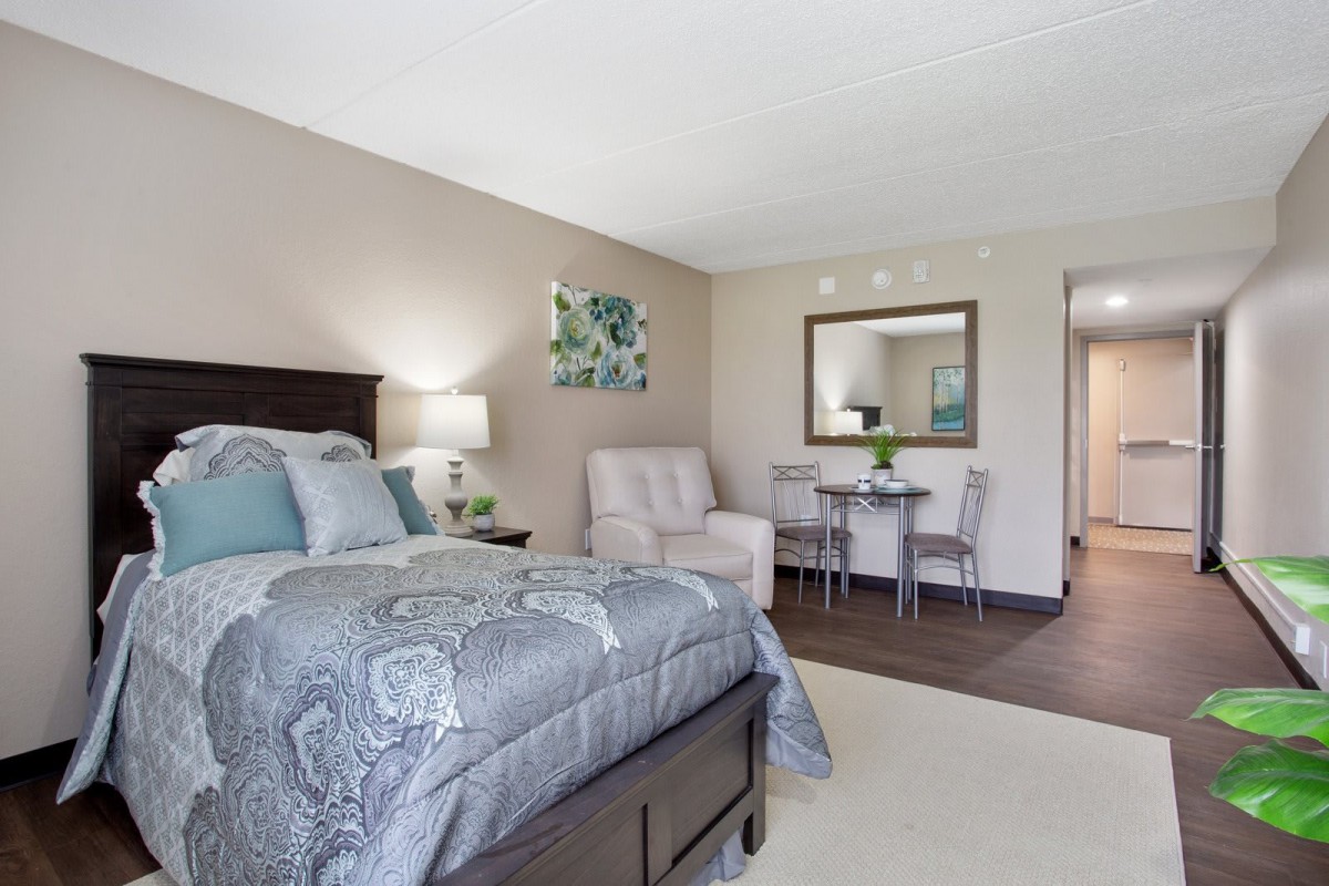 A modern bedroom with a comfortable bed, stylish decor, and a small seating area.