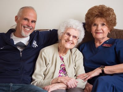A joyful family gathering with three smiling members, showcasing togetherness.