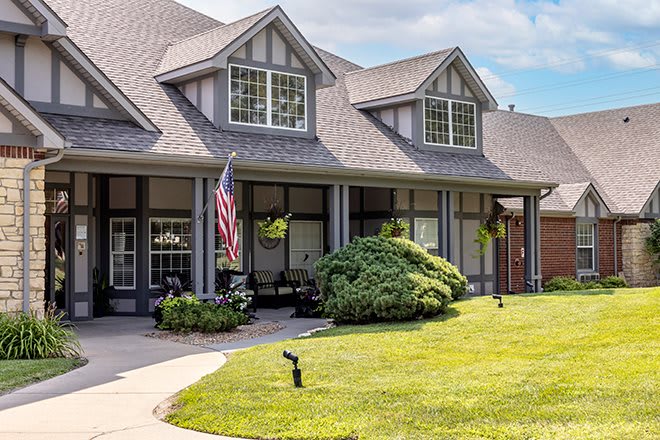A picturesque suburban house with a well-maintained lawn and an American flag displayed on the porch.