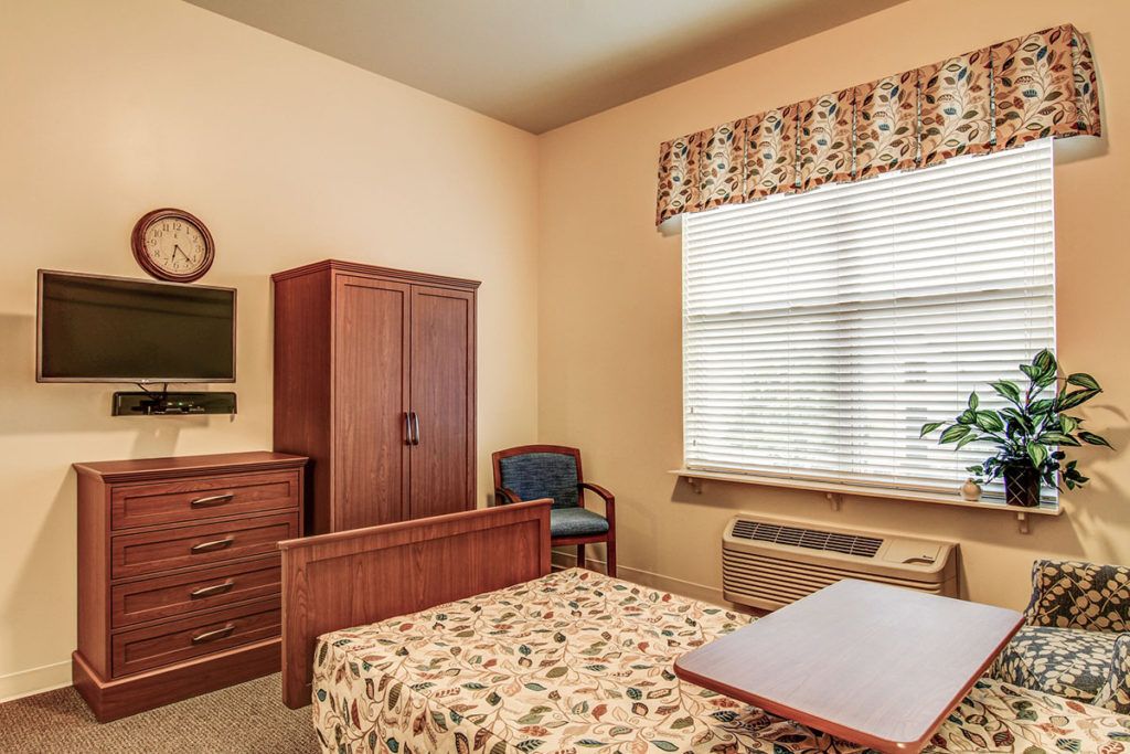 A cozy bedroom with a wooden wardrobe, dresser, and bed near a window.
