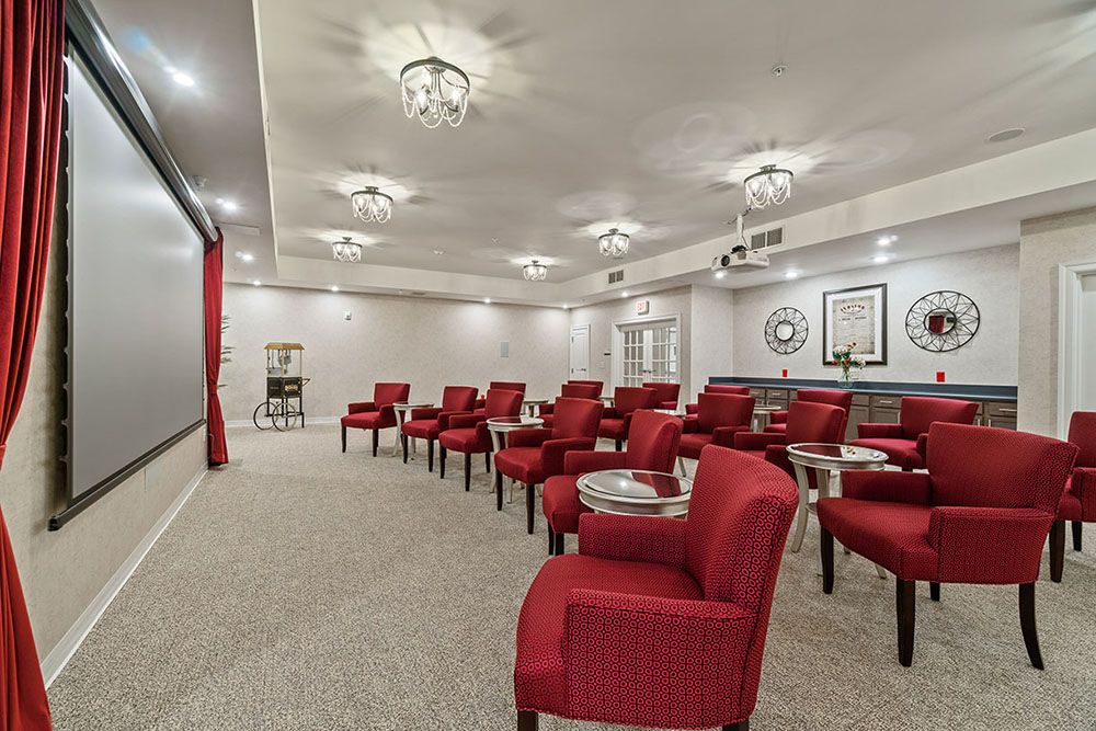 A cozy theater-style room with red chairs and a large screen.