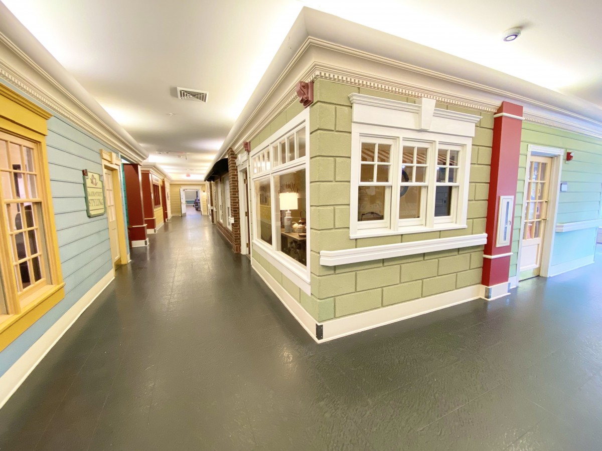 A well-lit indoor hallway decorated with house-like facades and large windows.