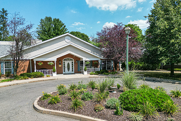 A scenic view of a building entrance surrounded by lush greenery and a well-maintained garden.