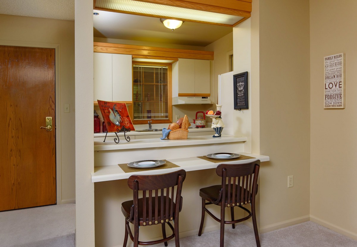 A cozy kitchen with a dining counter and bar stools, featuring warm lighting and decor.