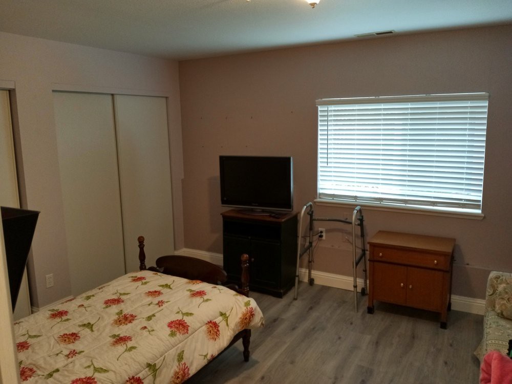 A cozy bedroom featuring a bed with floral bedding, a TV, and a window with blinds.