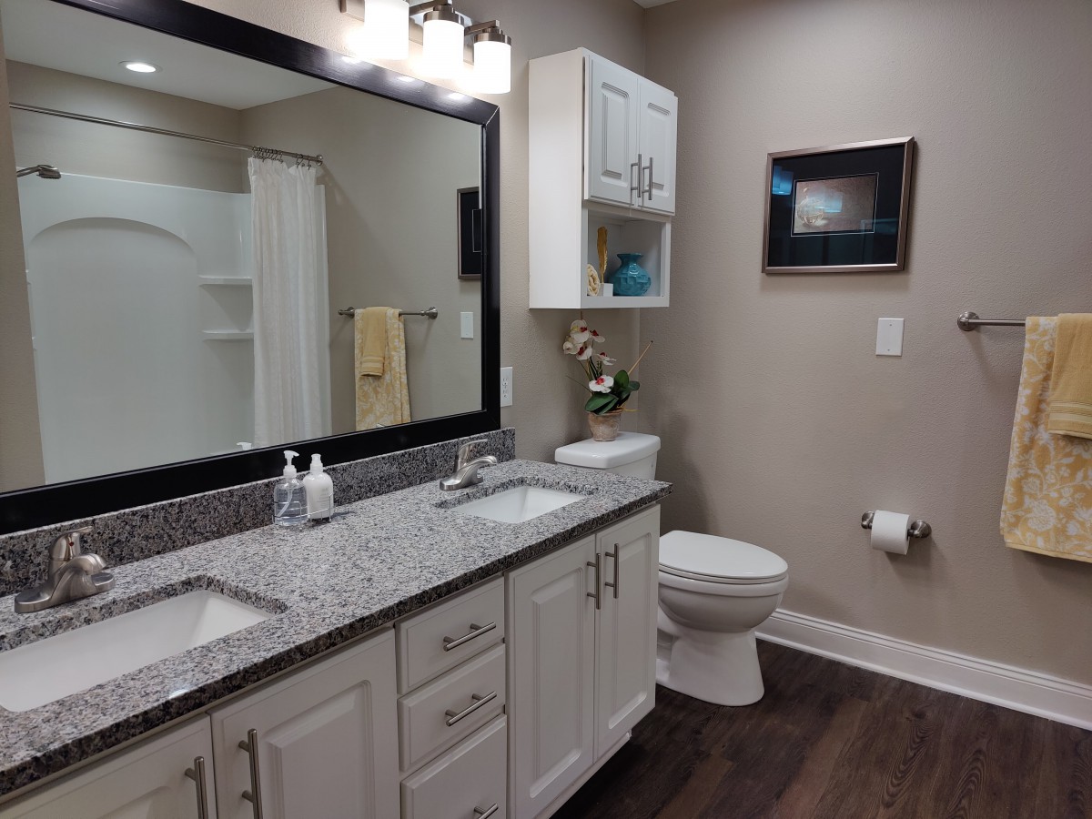 A modern bathroom with a large mirror, dual sinks, and granite countertops.