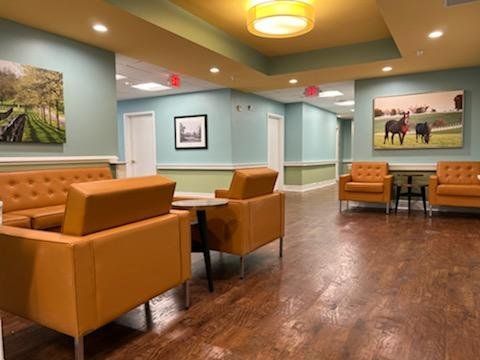 A cozy waiting room with orange chairs and wall art.