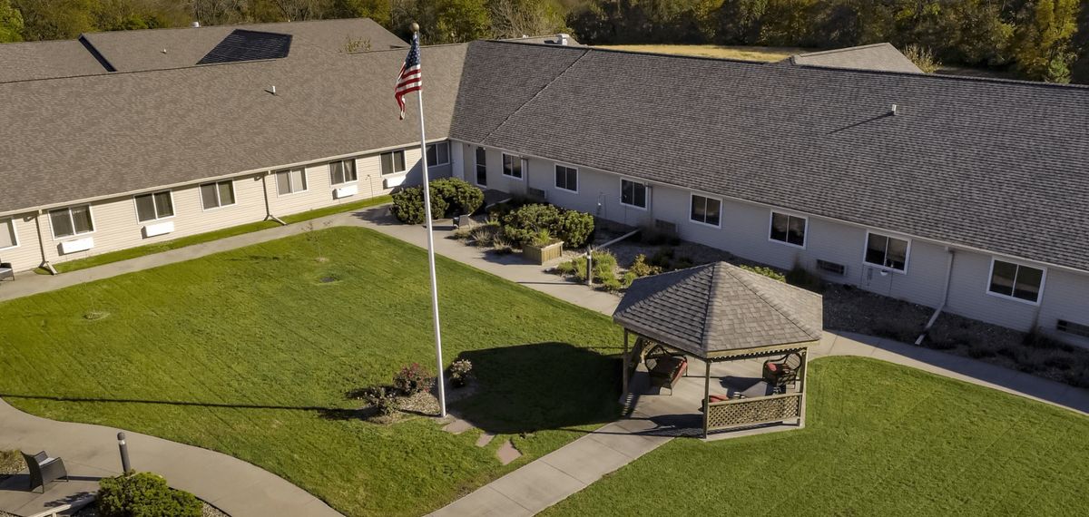 Aerial view of a building with a gazebo, flagpole, and well-maintained lawn.