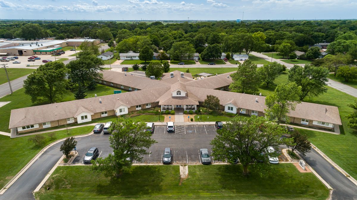 Aerial view of a building surrounded by trees and a parking lot.