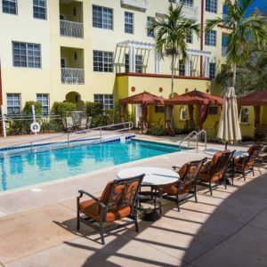 Outdoor pool area with loungers and umbrellas at an apartment complex.