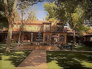 A beautiful house with a garden and fountain on a sunny day.