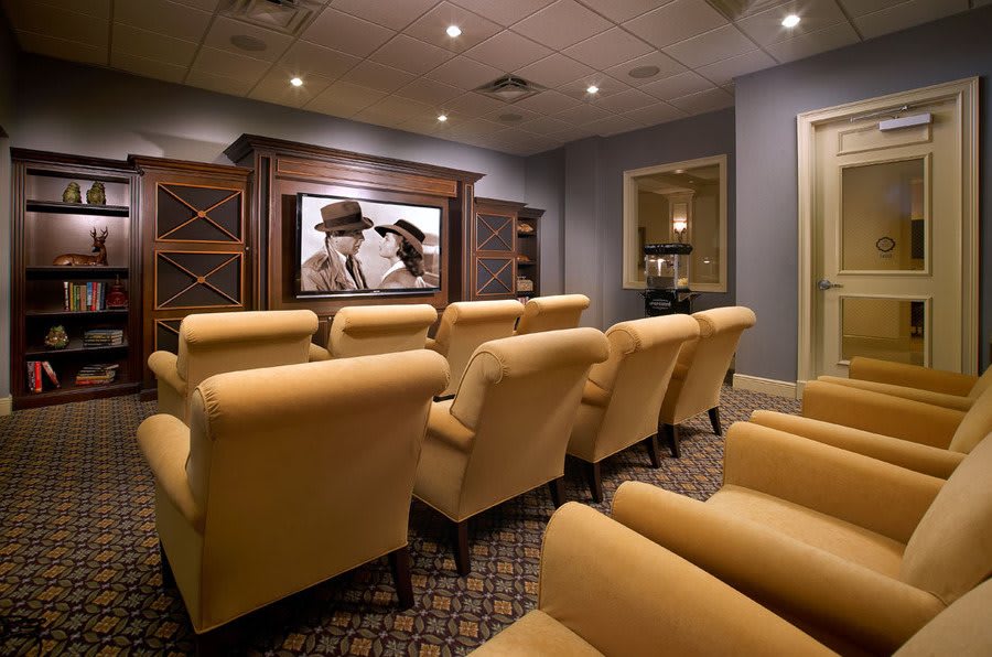 A cozy home theater setup featuring comfortable armchairs and a large screen displaying a classic film.