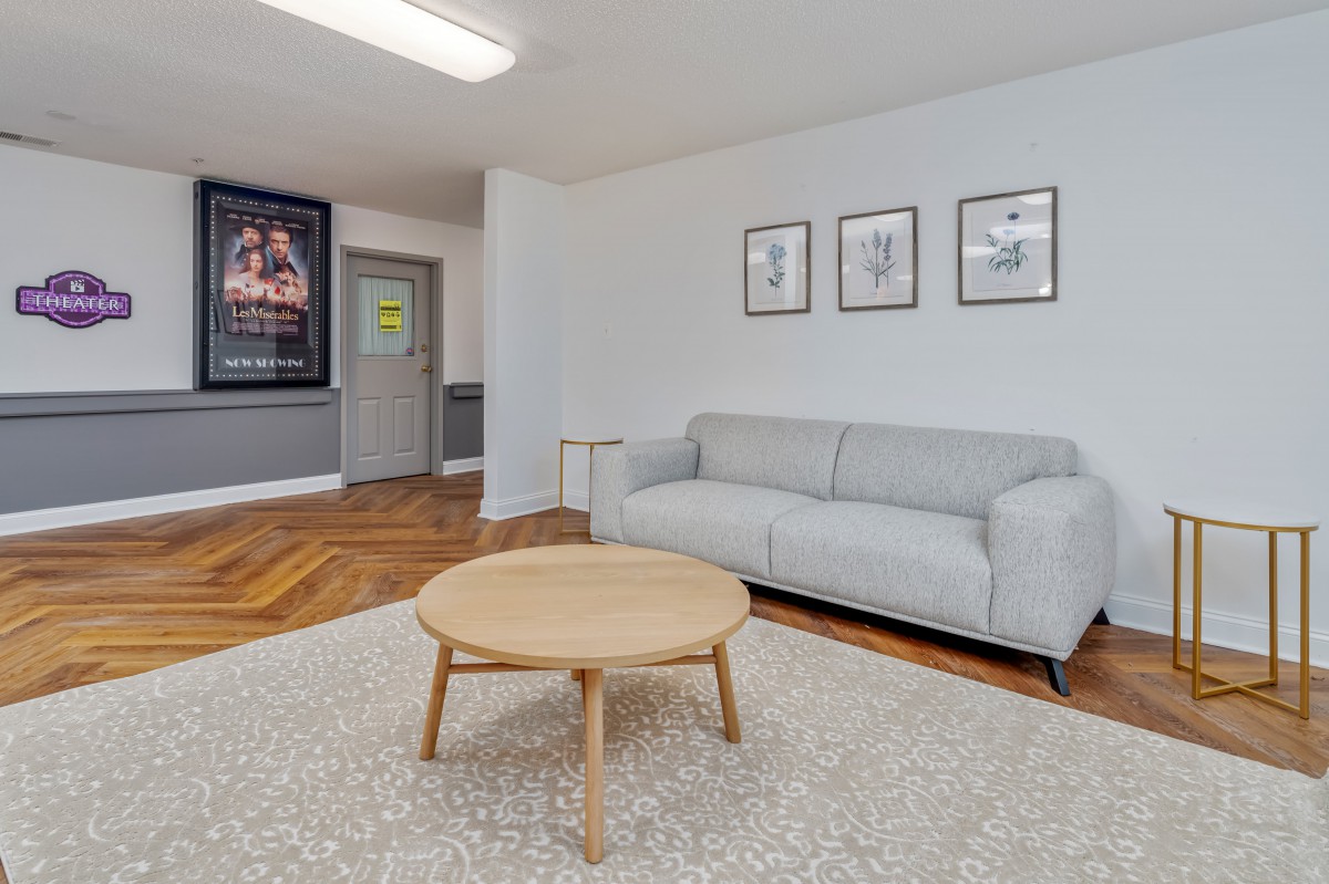 A cozy living room with a minimalist design featuring a gray sofa, wooden coffee table, and wall art.