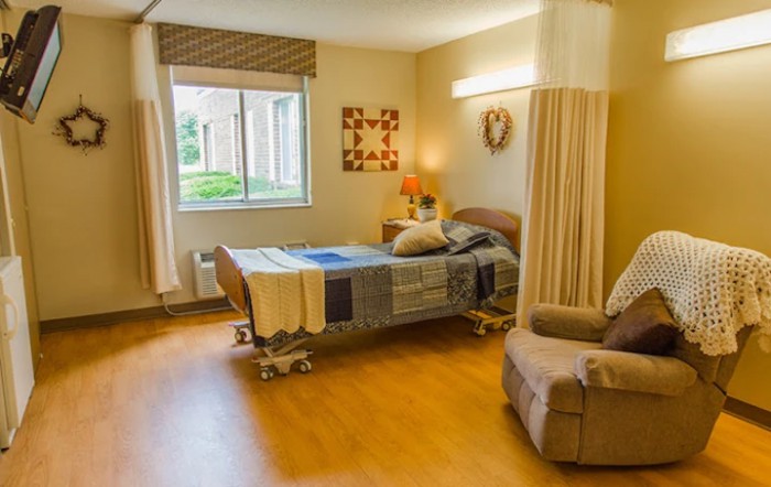 A cozy hospital room with a bed, chair, and decorative elements.