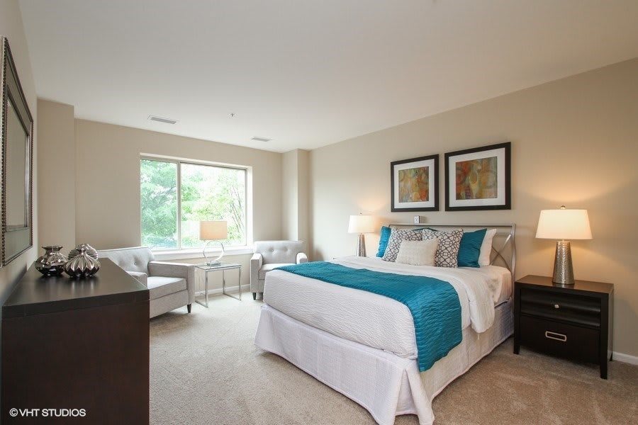 A modern bedroom with a large window, stylish furniture, and colorful accents.