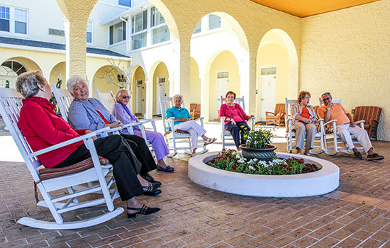 A group of seniors enjoying a leisurely afternoon in rocking chairs at a retirement community courtyard.