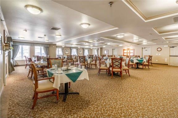 An elegant restaurant dining room with neatly arranged tables and chairs, featuring a carpeted floor.