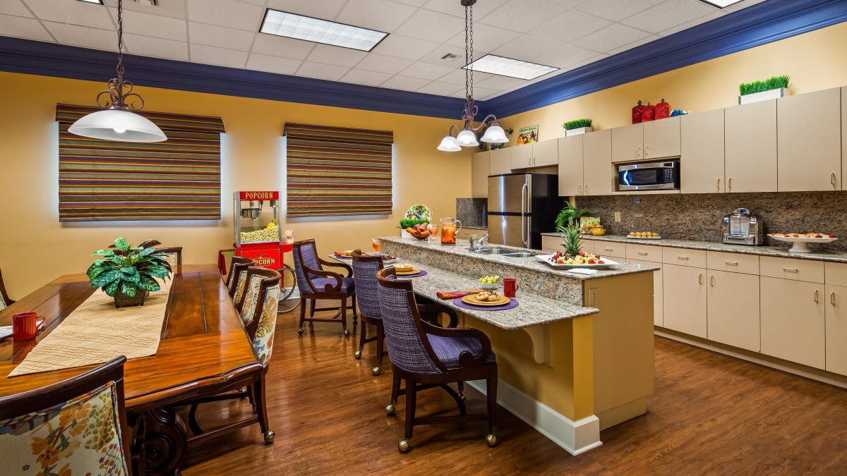 A spacious and modern kitchen with a dining area, featuring a long counter with chairs, contemporary appliances, and stylish decor.