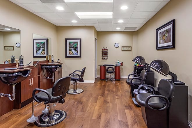 A well-lit barber shop interior with multiple chairs and mirrors, featuring wooden flooring and stylish decor.