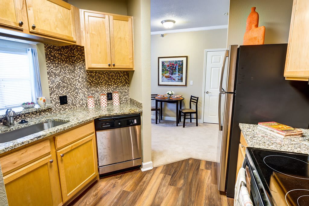 A modern kitchen with wooden cabinets and stainless steel appliances opens to a cozy dining area.