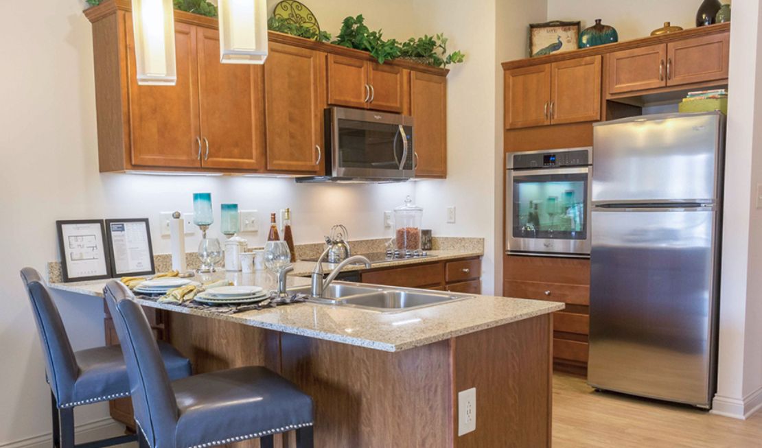 A modern kitchen with wooden cabinets, an island countertop, and stainless steel appliances.