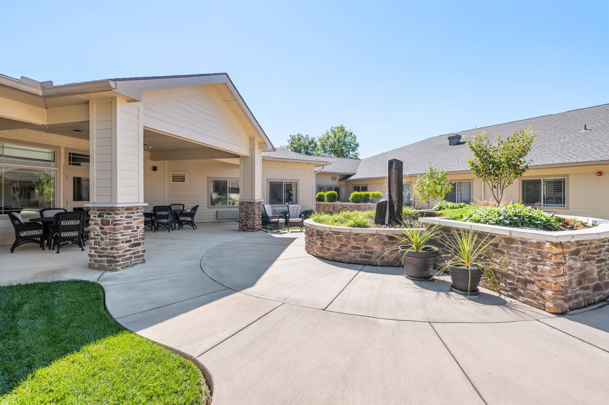 A modern house with a spacious patio and well-maintained garden under clear blue skies.