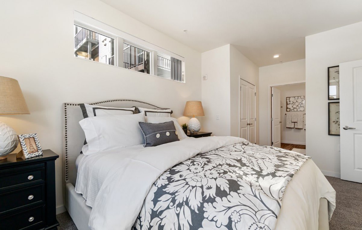 A modern, bright bedroom with stylish decor and cozy bedding.