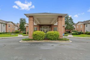 A building entrance with a covered driveway and landscaped greenery.