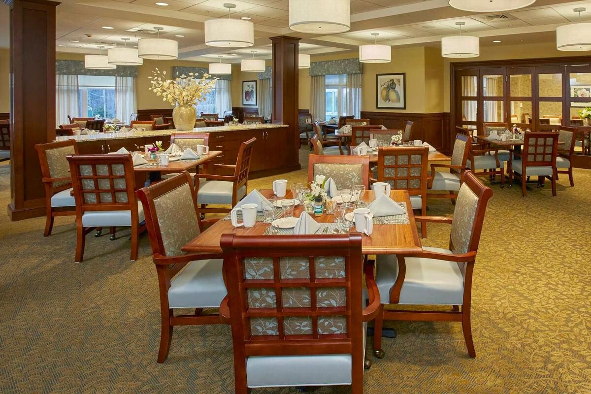 A well-lit dining area with neatly arranged tables and chairs, featuring a cozy and elegant interior design.