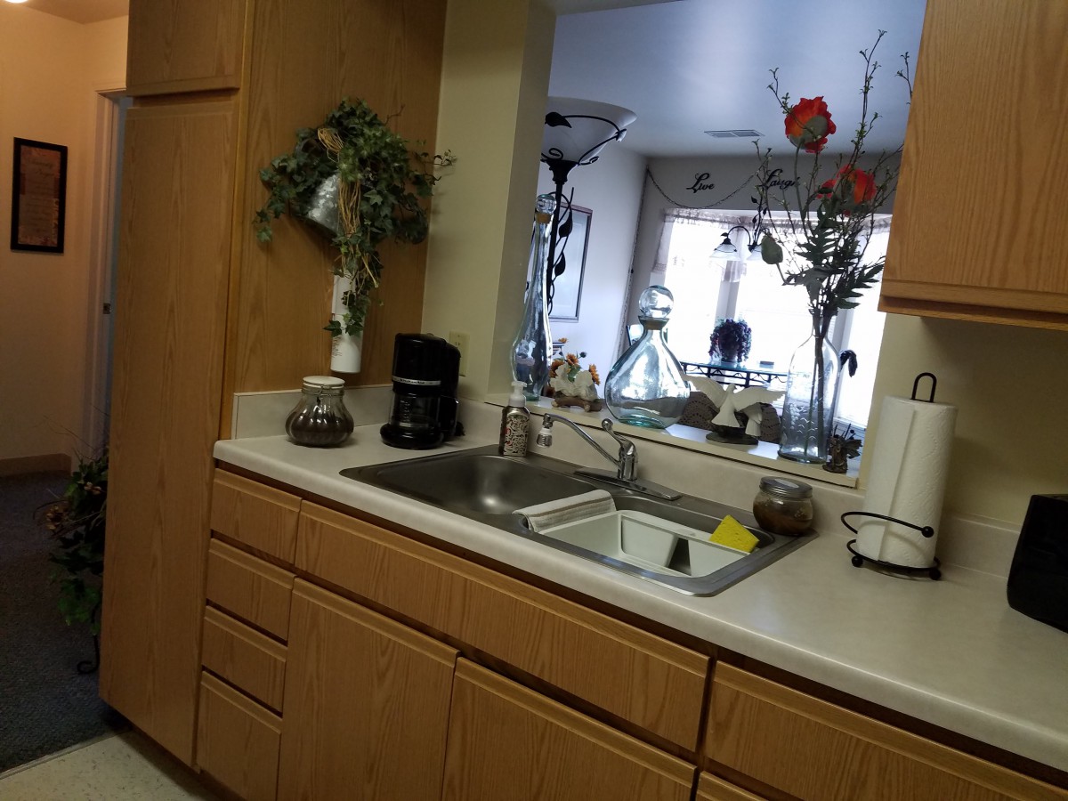A kitchen with wooden cabinets, a sink, and various appliances and decorations.