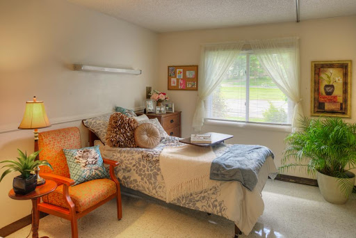 A cozy and well-lit bedroom with soft decor, featuring a comfortable bed and an inviting chair.