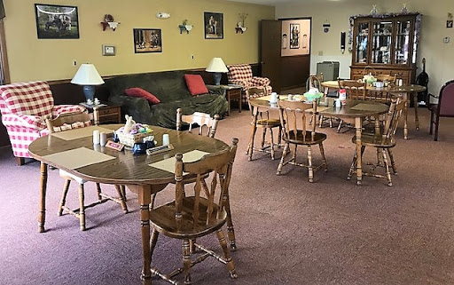 A cozy dining area featuring wooden tables and chairs, a comfortable sofa, and warm lighting.