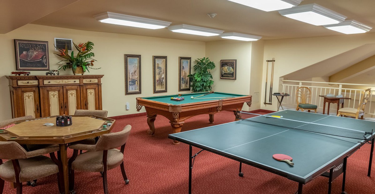 A game room featuring a pool table and a ping pong table, with chairs and wall decorations.