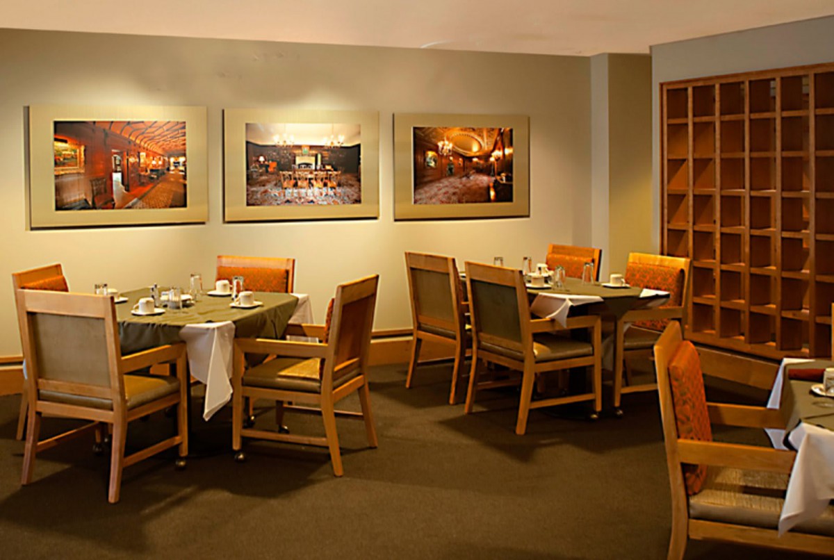 A cozy restaurant dining area with neatly arranged tables and chairs, adorned with artwork on the walls.