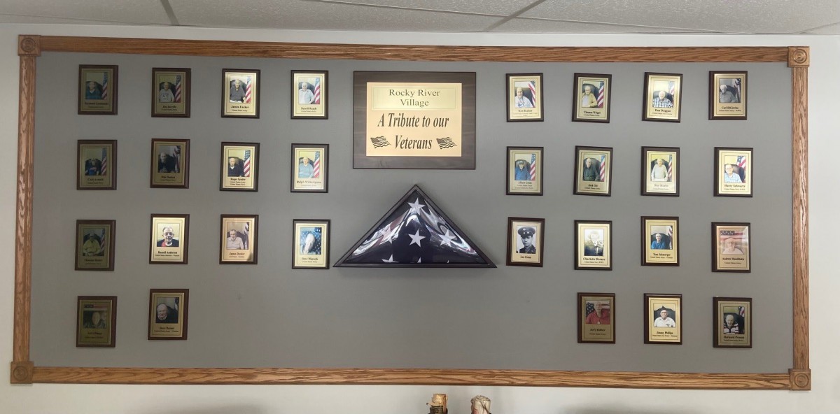 A wall display featuring framed photographs and a folded American flag in honor of military service.