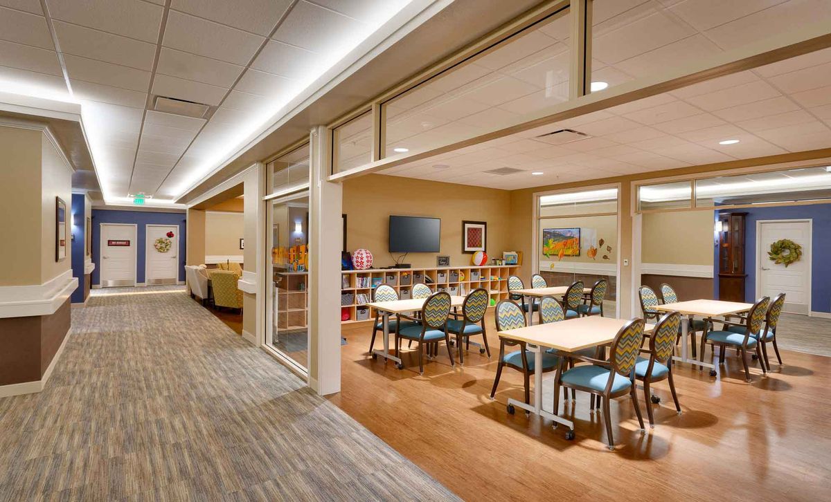 A well-lit interior lounge area with tables, chairs, and a television.