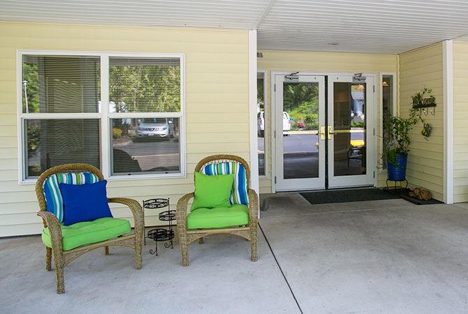 A cozy entrance area with wicker chairs and colorful cushions.