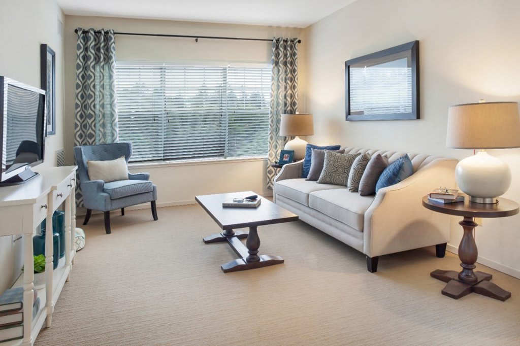 A cozy and modern living room with a sofa, armchair, and coffee table near a large window.