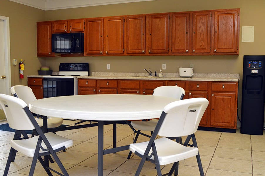 A kitchen with wooden cabinets, a round table, and folding chairs.