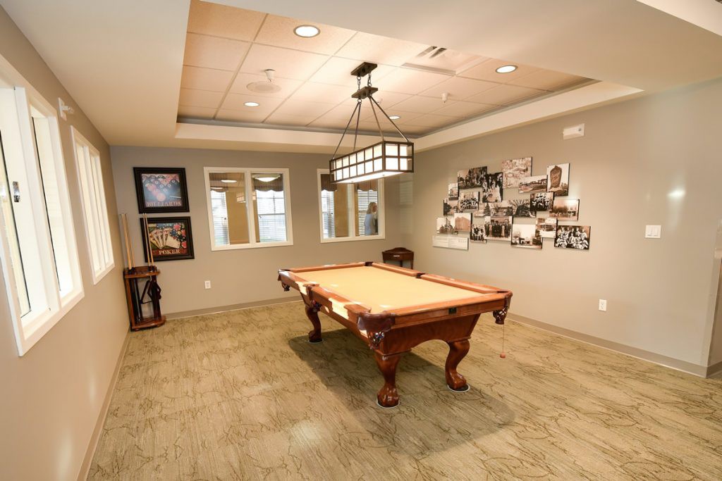 A cozy billiard room with a classic pool table, stylish lighting, and vintage wall decor.