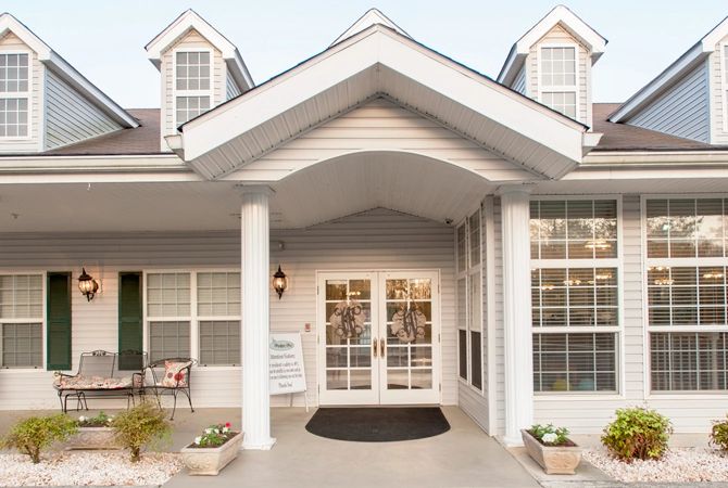 A residential building entrance with white columns and large windows.
