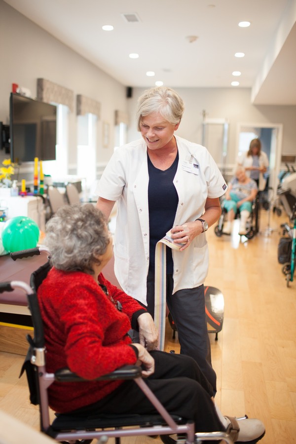 A caregiver interacting with an elderly woman in a nursing home setting.