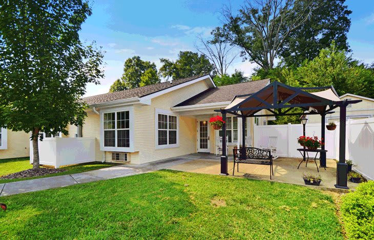A cozy house with a well-maintained lawn and a patio area on a sunny day.